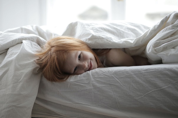 Smiling girl in bed on a soft mattress